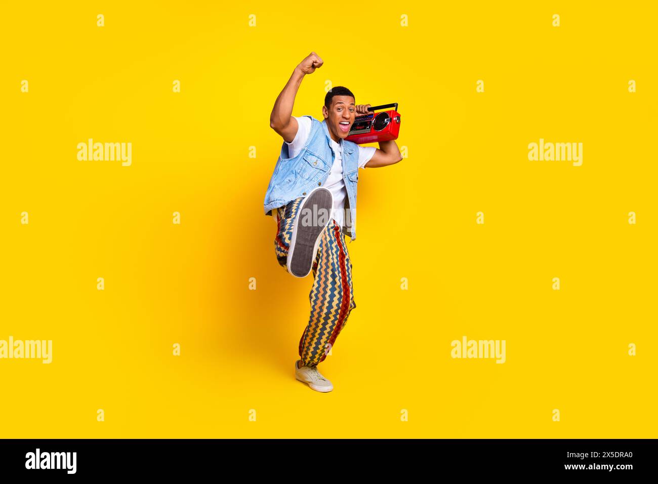 Full size photo of satisfied man dressed denim vest hold retro boombox scream yeah hand up isolated on vibrant yellow color background Stock Photo