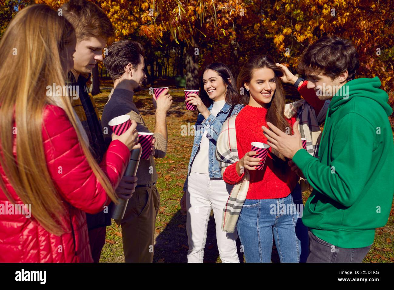 Happy friends having fun standing together with drinks in park Stock Photo