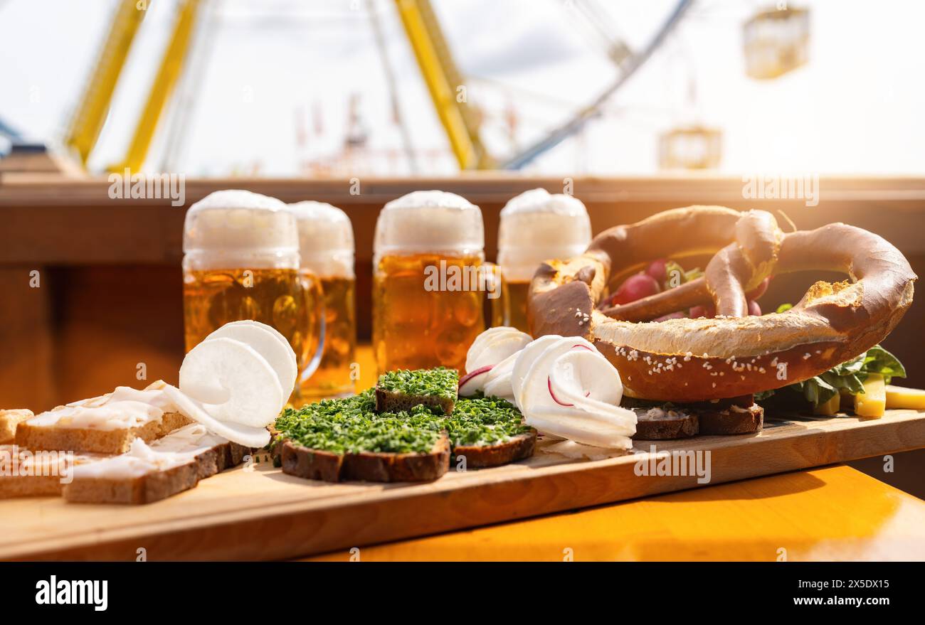 Traditional German food and beer mugs on a wooden tray with ferris wheel ride in the background at oktoberfest or  dult in germany Stock Photo