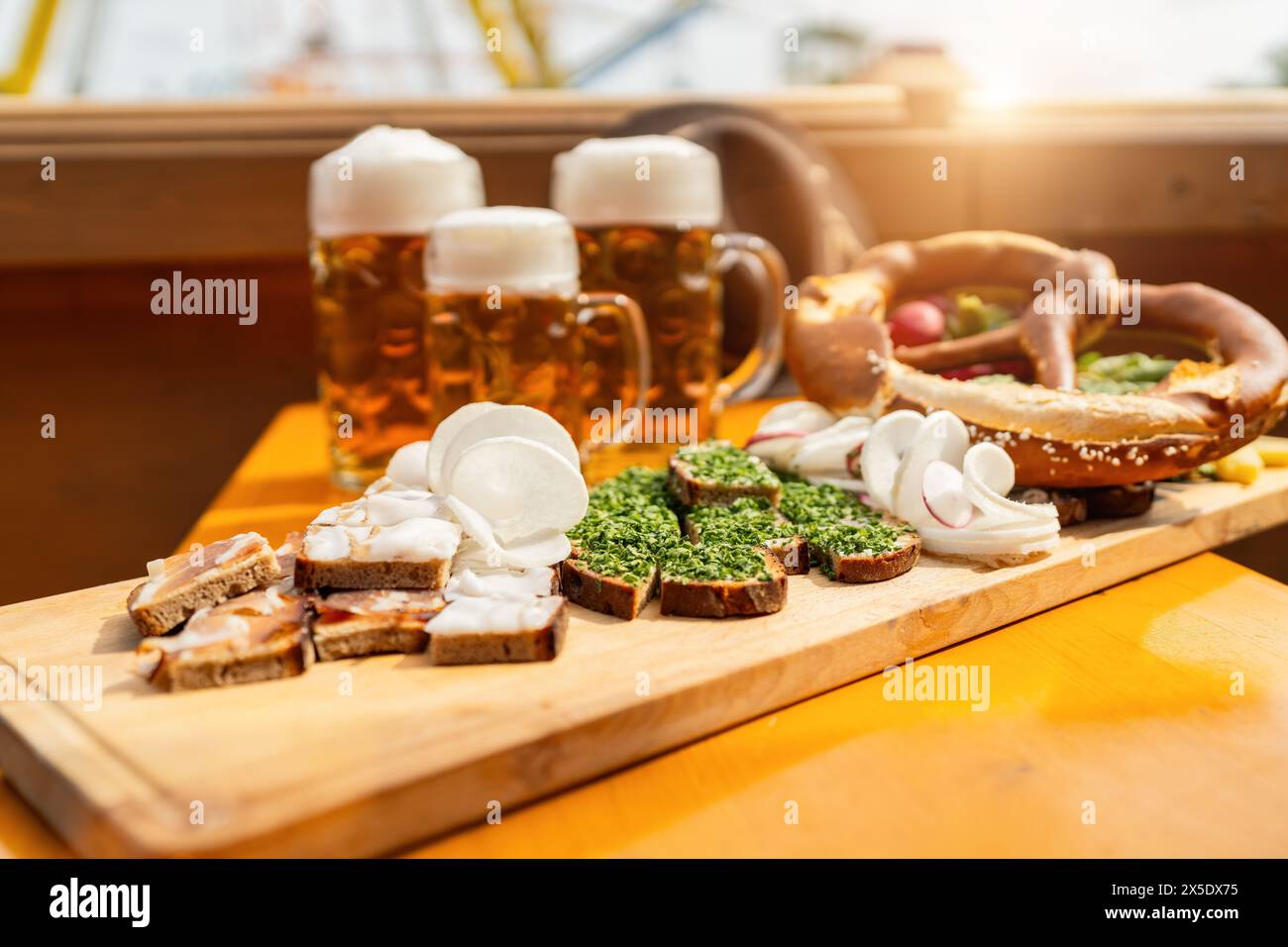 Traditional German beer mugs and food on a wooden tray in a beer tent with ferris wheel ride in the background at oktoberfest or  dult in germany Stock Photo