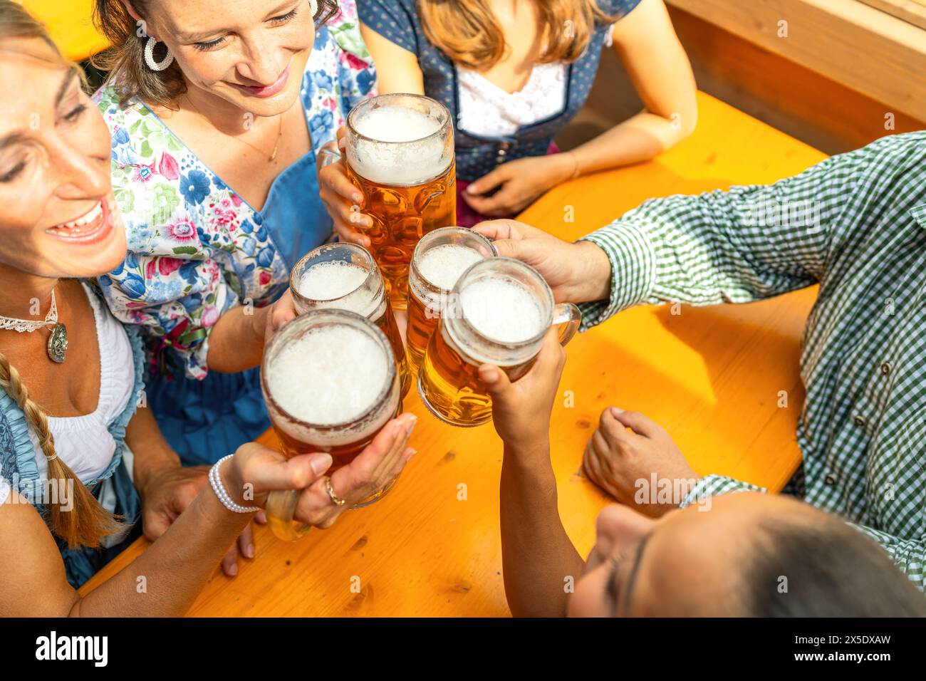 Group of people in traditional Bavarian outfits or tracht toasting with ...