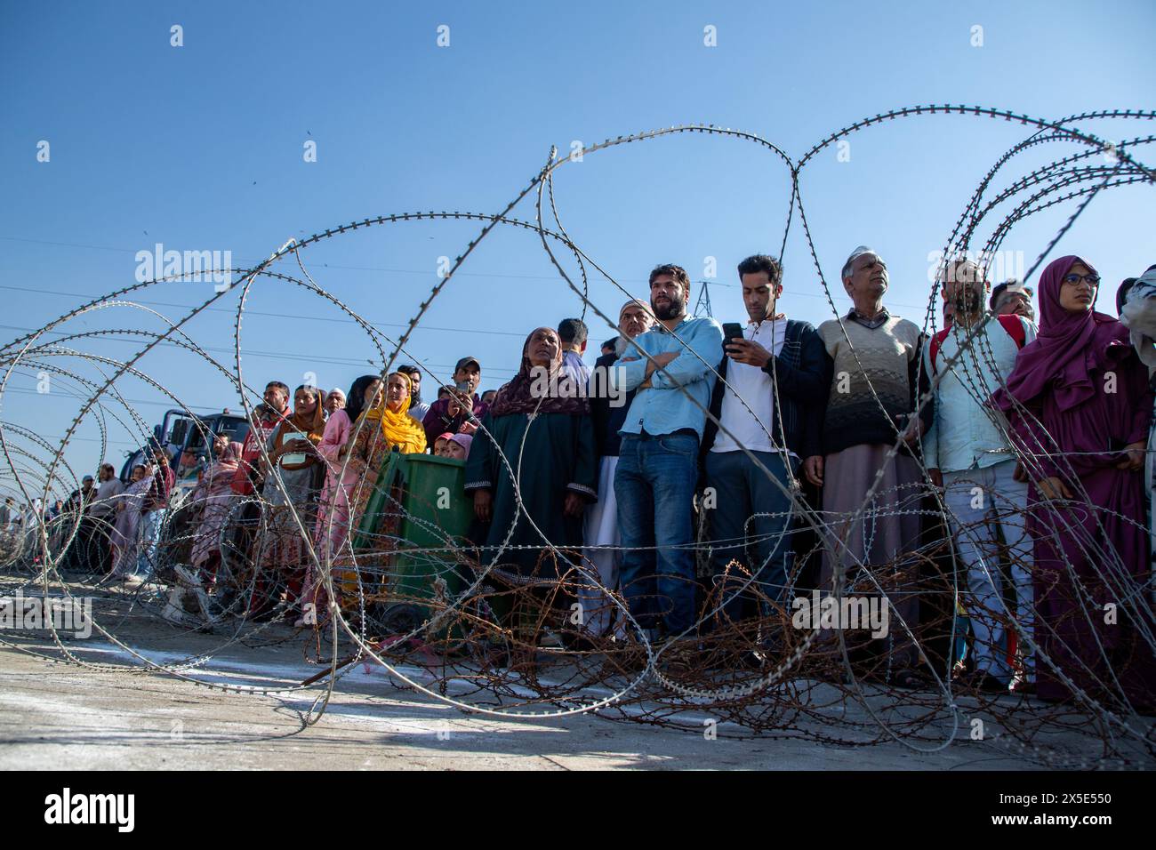 Relatives watch from behind concertina wire as Kashmiri Muslim pilgrims leave for the annual hajj pilgrimage to the holy city of Mecca in Srinagar. The first batch of Hajj pilgrims from Jammu and Kashmir will leave for Saudi Arabia from Srinagar International Airport on Thursday. Officials said that this year, 7008 pilgrims from Jammu and Kashmir will perform the holiest Muslim pilgrimage of Hajj in Saudi Arabia. (Photo by Faisal Bashir / SOPA Images/Sipa USA) Stock Photo