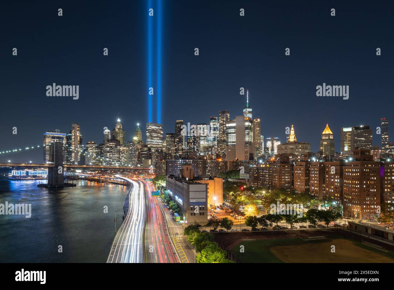 September 11 Tribute in Light with the skycrapers of Lower Manhattan at night. View of Brooklyn Bridge and East River. New York City Stock Photo