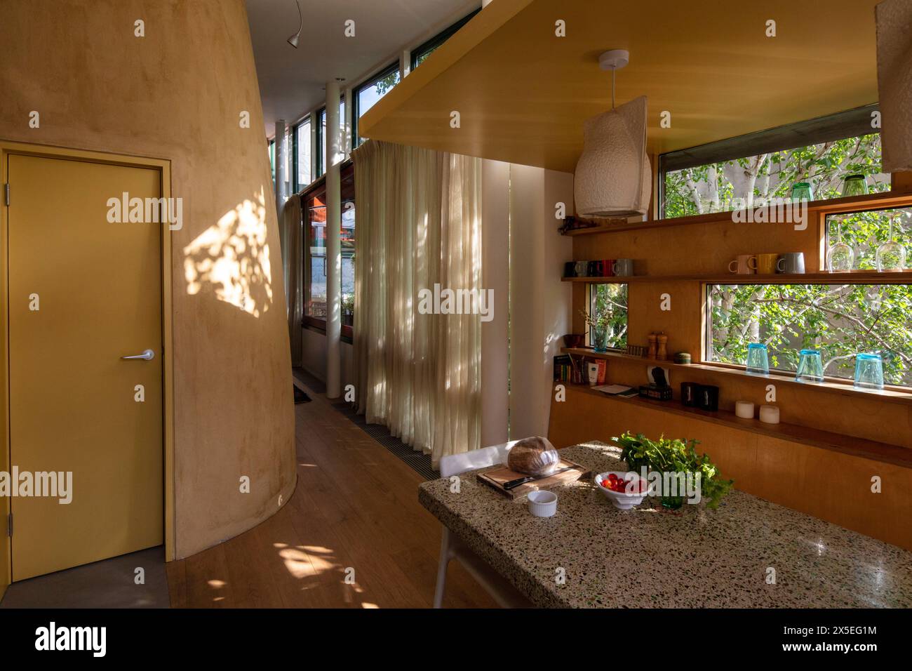 Oblong windows run down the side of the kitchen area. Straw Bale House