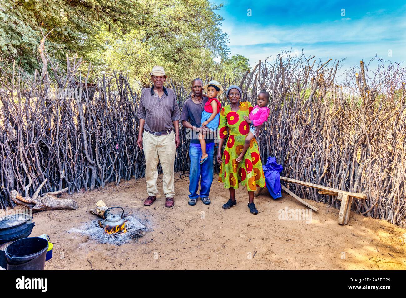 African village, large family standing parents and kids in the outdoors kitchen, teapot on the fire Stock Photo