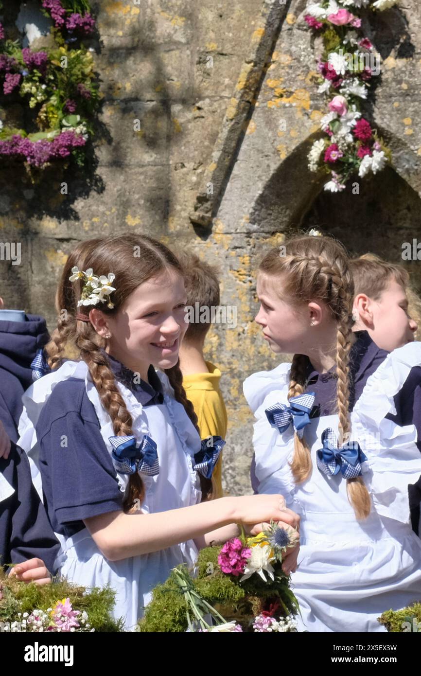 Bisley, Glos, UK. 9th May, 2024. In a traditional Cotswold activity, children from Blue Coat primary school celebrate Ascension Day by parading through the village. The children are wearing traditional Victorian style uniforms. Flower garlands are carried to the Wells which they then decorate. The tradition started in 1863 when the Vicar, the Reverend Keble gave thanks for the villages clean water. Credit: JMF News/Alamy Live News Stock Photo