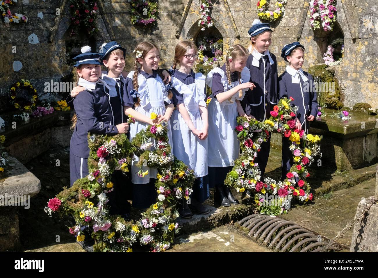 Bisley, Glos, UK. 9th May, 2024. In a traditional Cotswold activity, children from Blue Coat primary school celebrate Ascension Day by parading through the village. The children are wearing traditional Victorian style uniforms. Flower garlands are carried to the Wells which they then decorate. The tradition started in 1863 when the Vicar, the Reverend Keble gave thanks for the villages clean water. Credit: JMF News/Alamy Live News Stock Photo