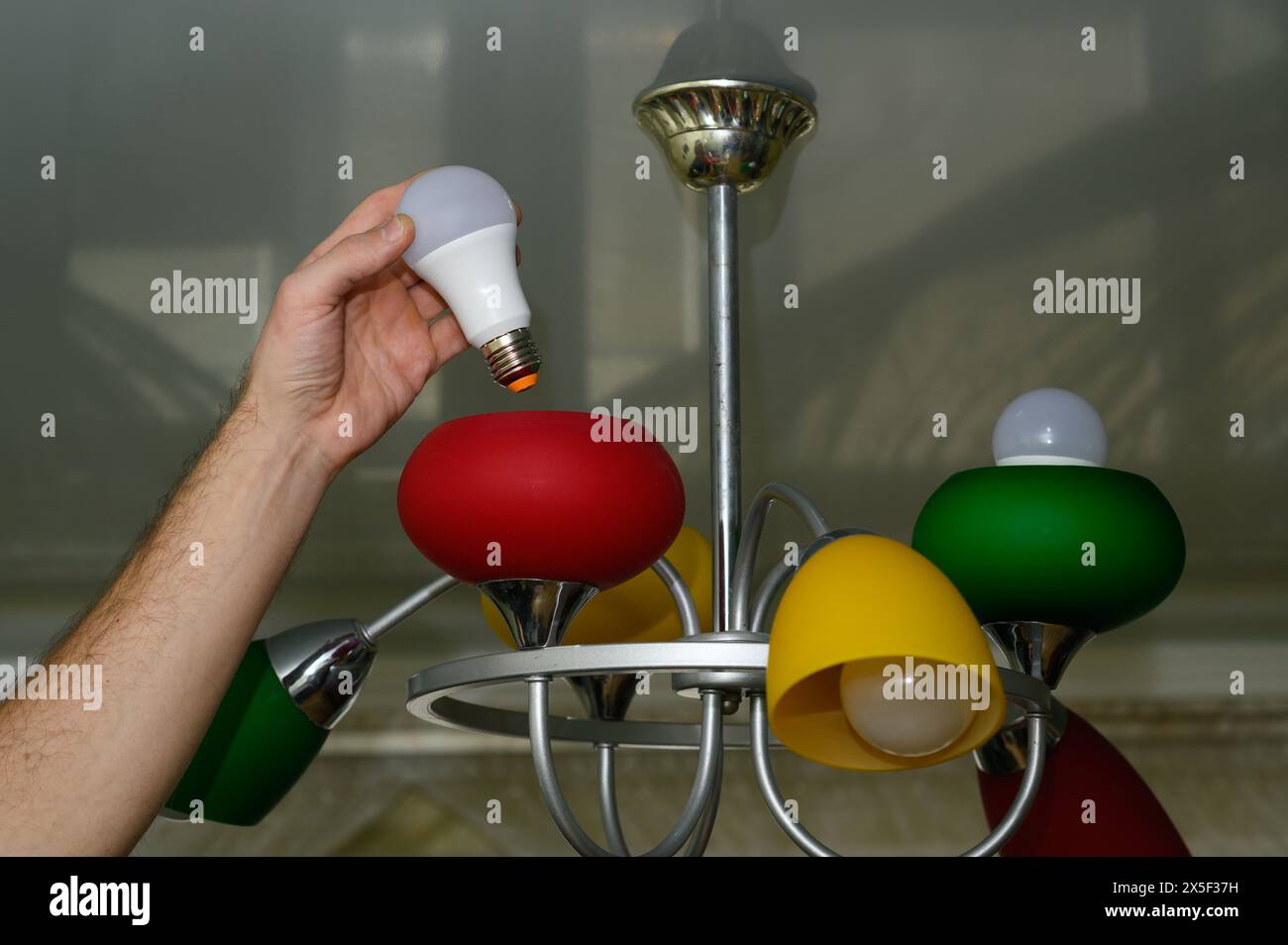 replacing the light bulb in the chandelier. LED lamp. Stock Photo