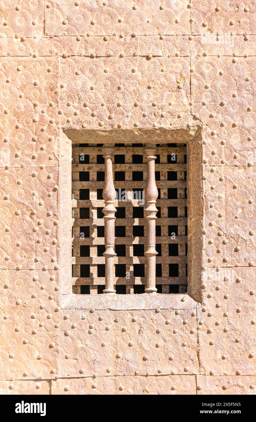 Medieval door with a peephole covered in metal bars in the old town of