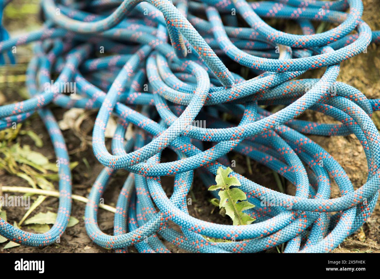 Rolled blue rope, rock climbing rope on ground . Close up view Stock Photo