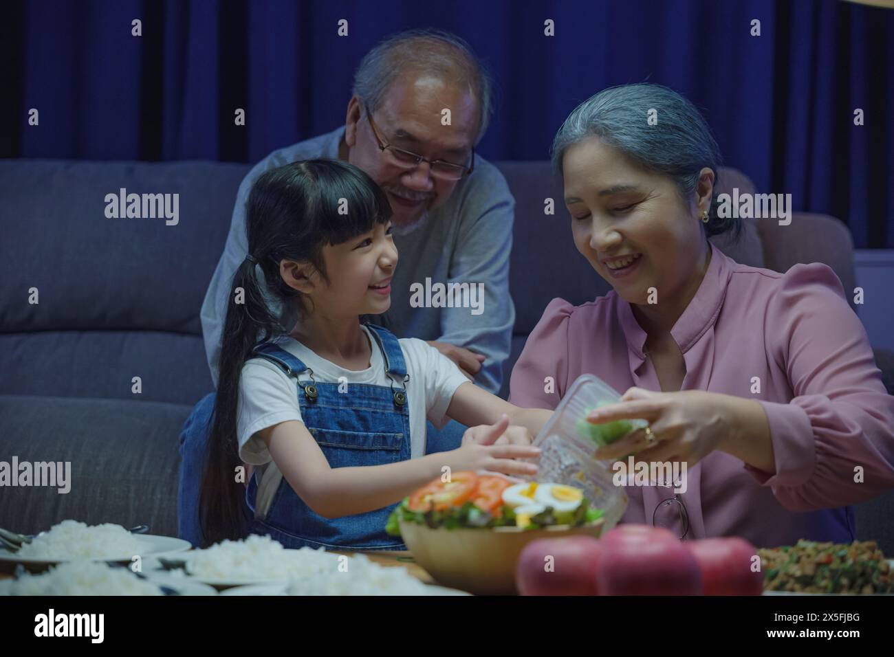 senior parent and child eating dinner food together in living room ...