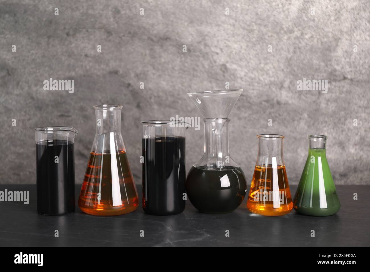 Beakers and flasks with different types of oil on grey textured table