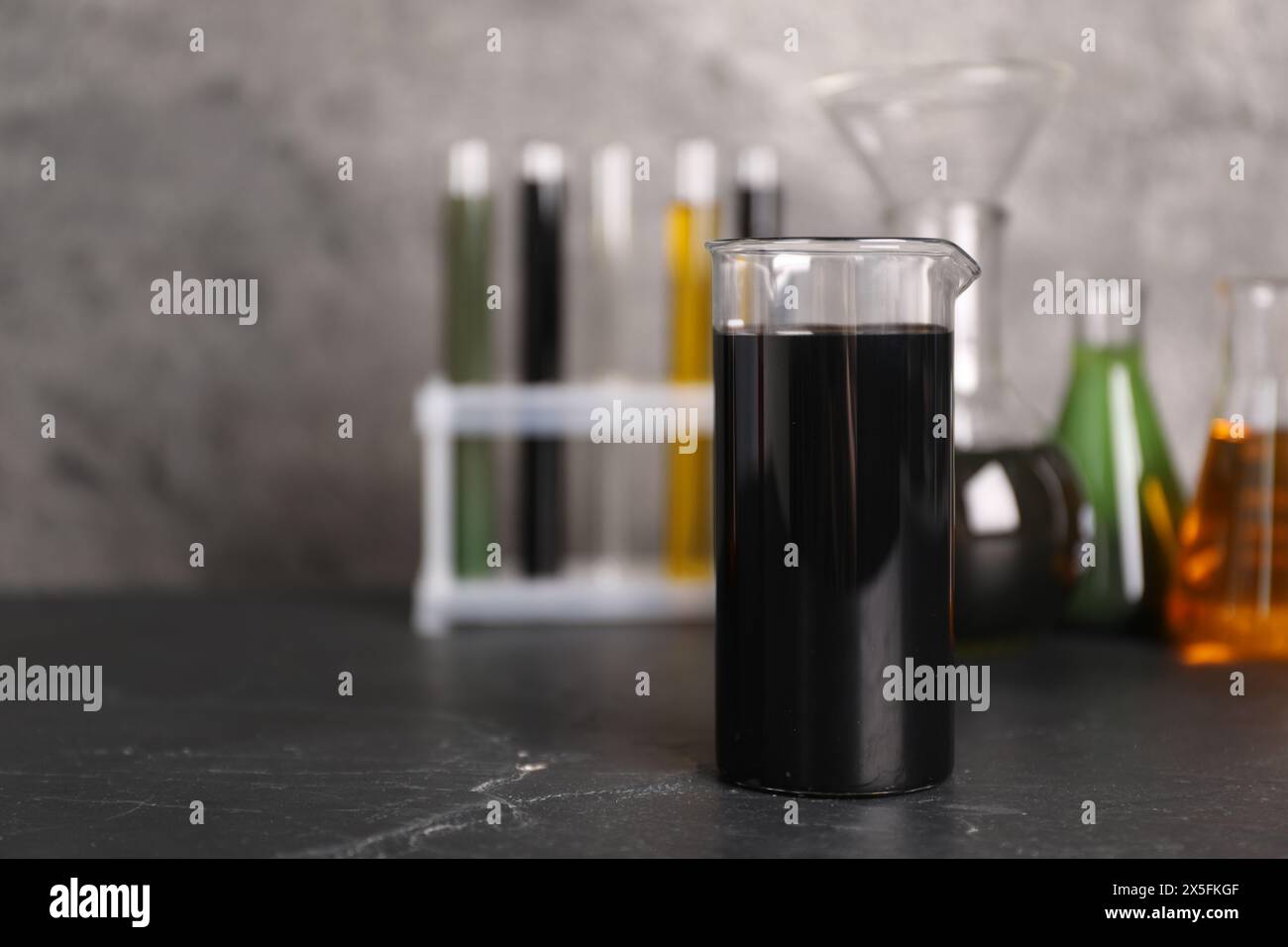 Beaker, flasks and test tubes with different types of oil on grey ...