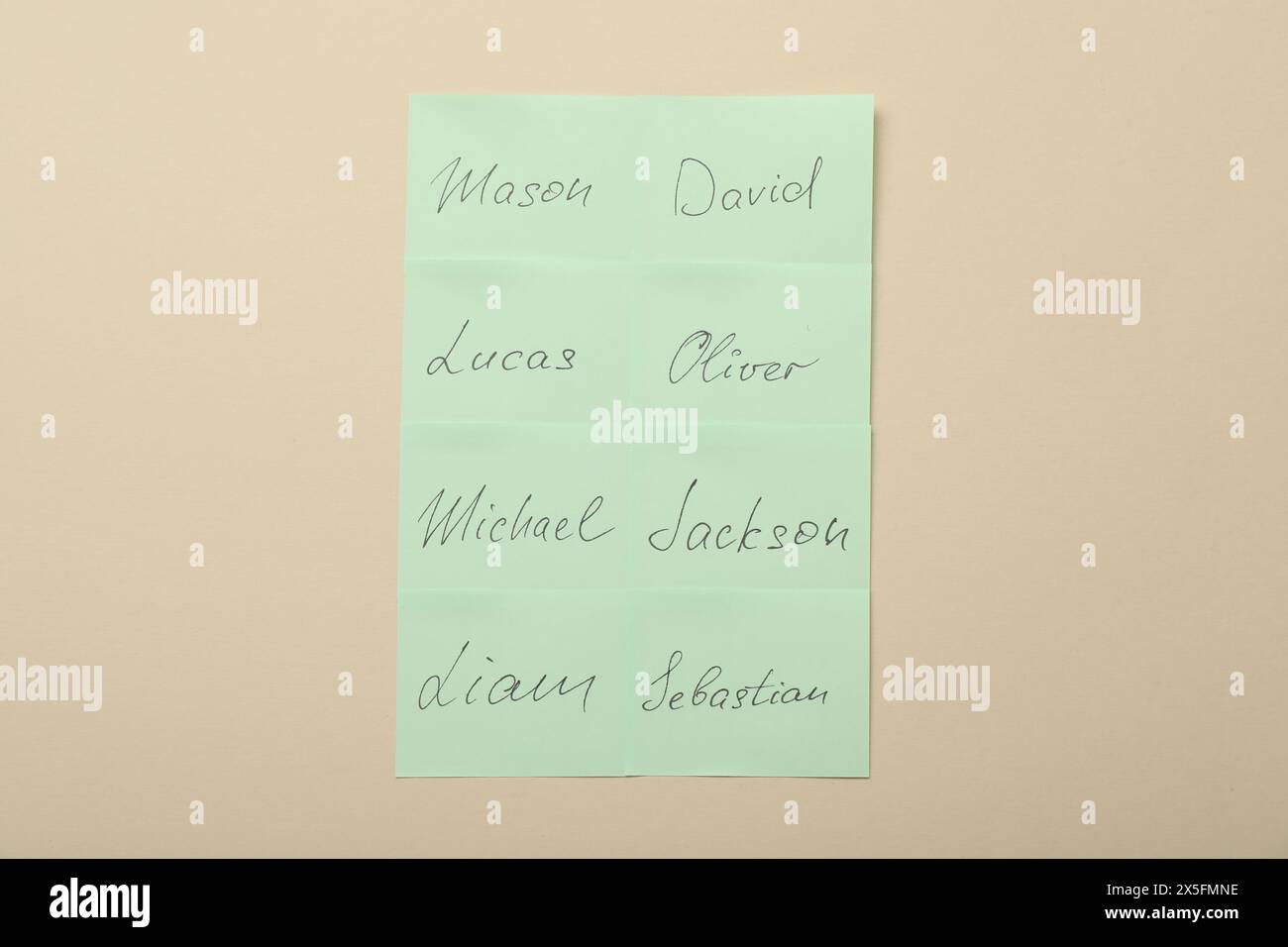 Paper stickers with different names on beige background, top view ...