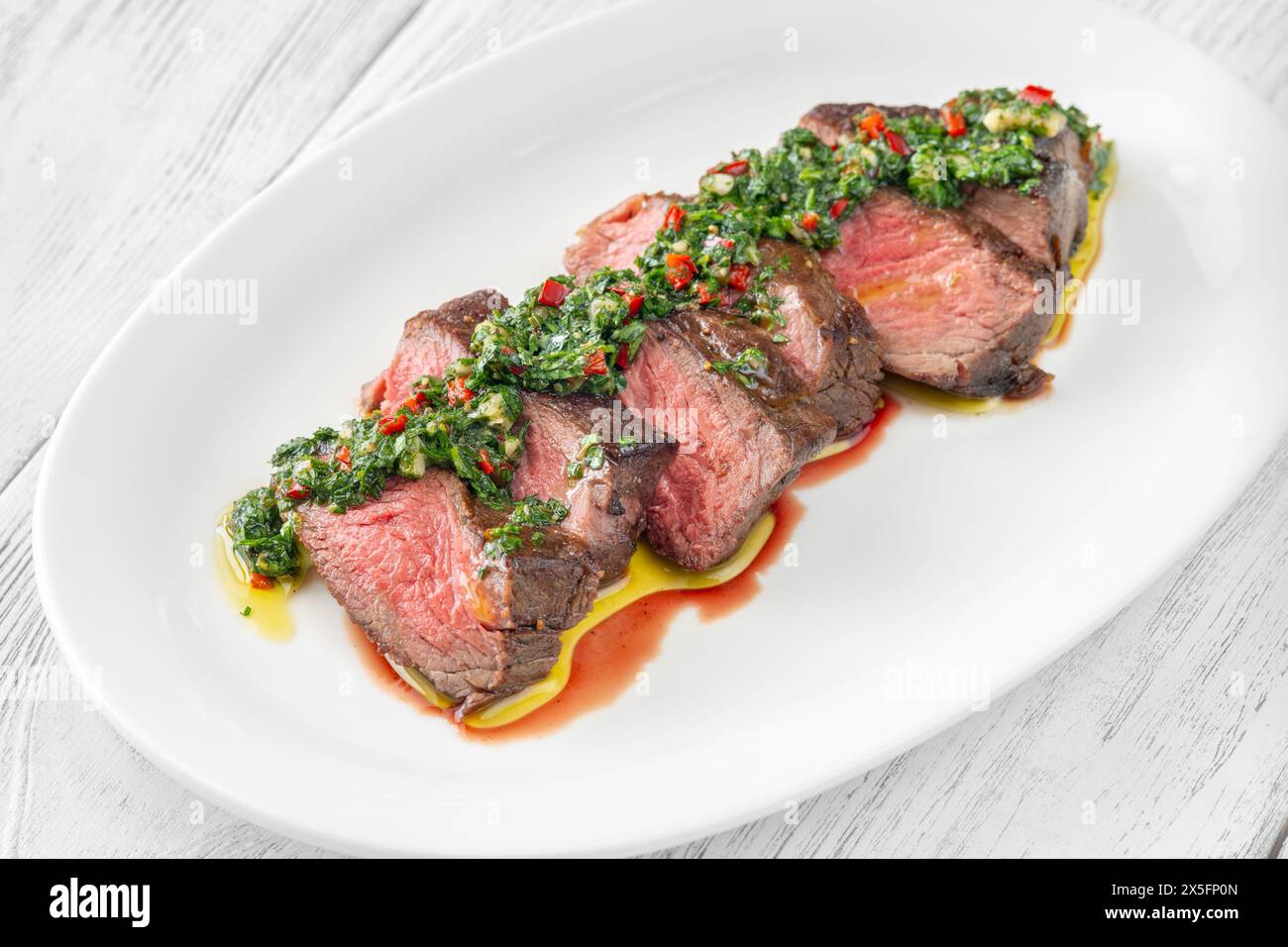 Portion of sliced strip steak with Chimichurri sauce Stock Photo