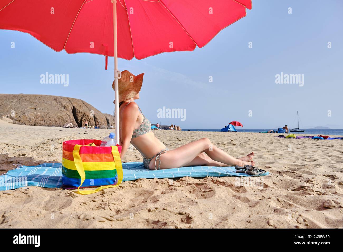 Anonymous woman in hat sitting on beach Stock Photo