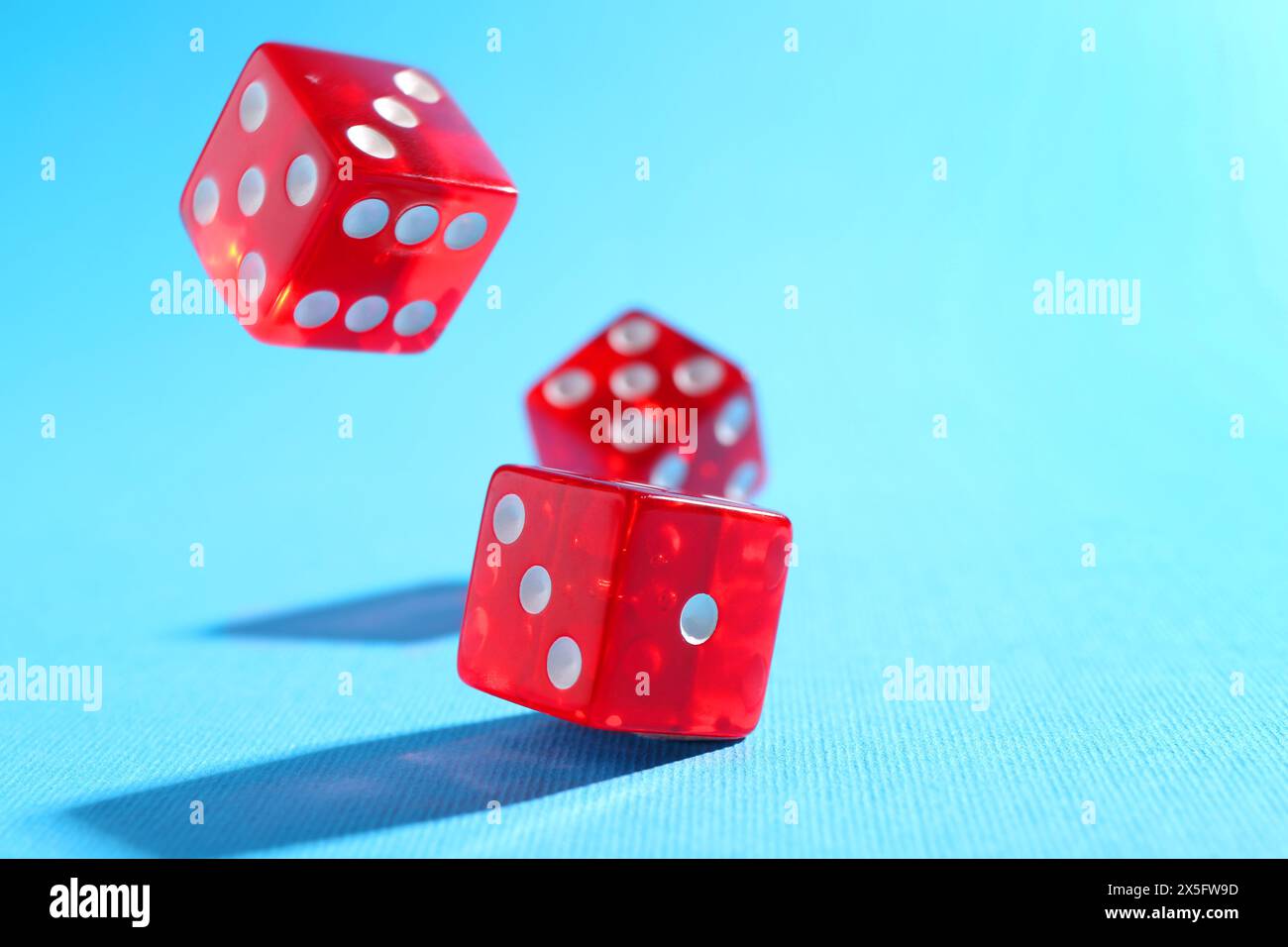 Three red game dices falling on light blue background, closeup. Space for text Stock Photo