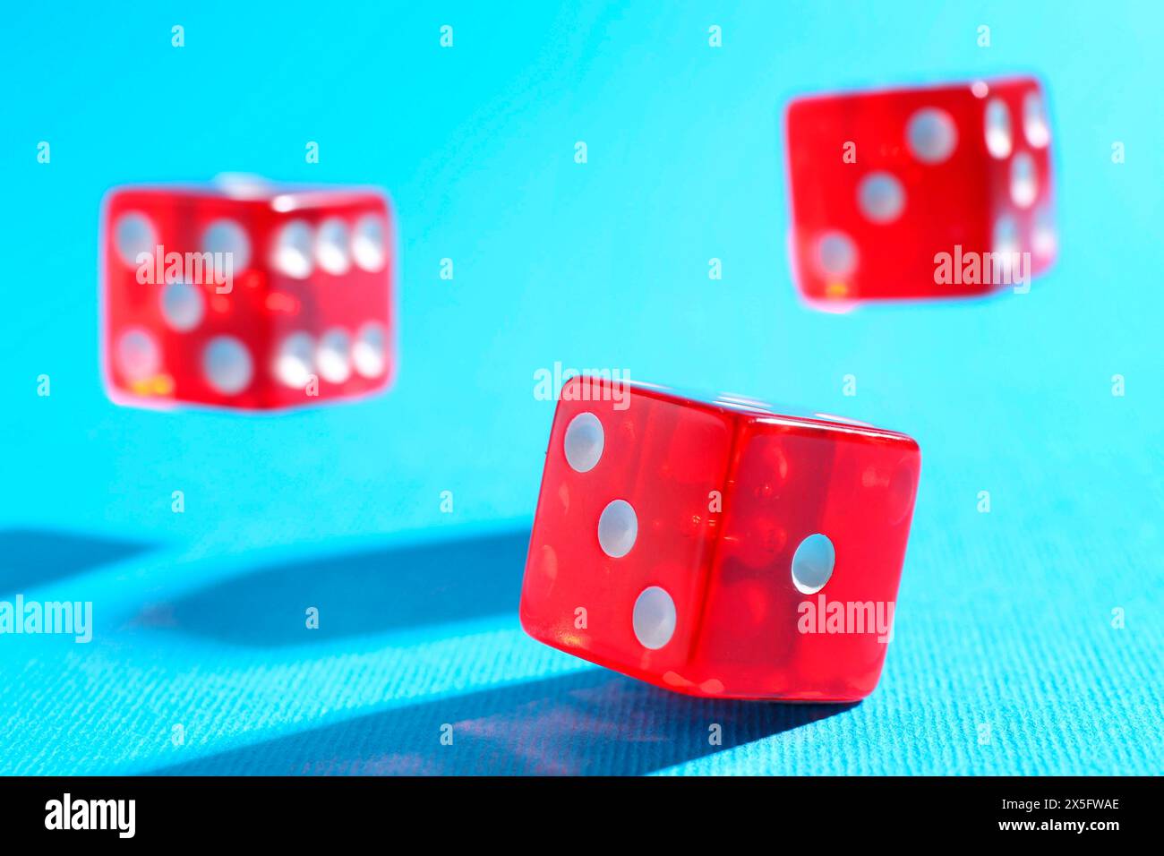 Three red game dices falling on light blue background, closeup Stock Photo