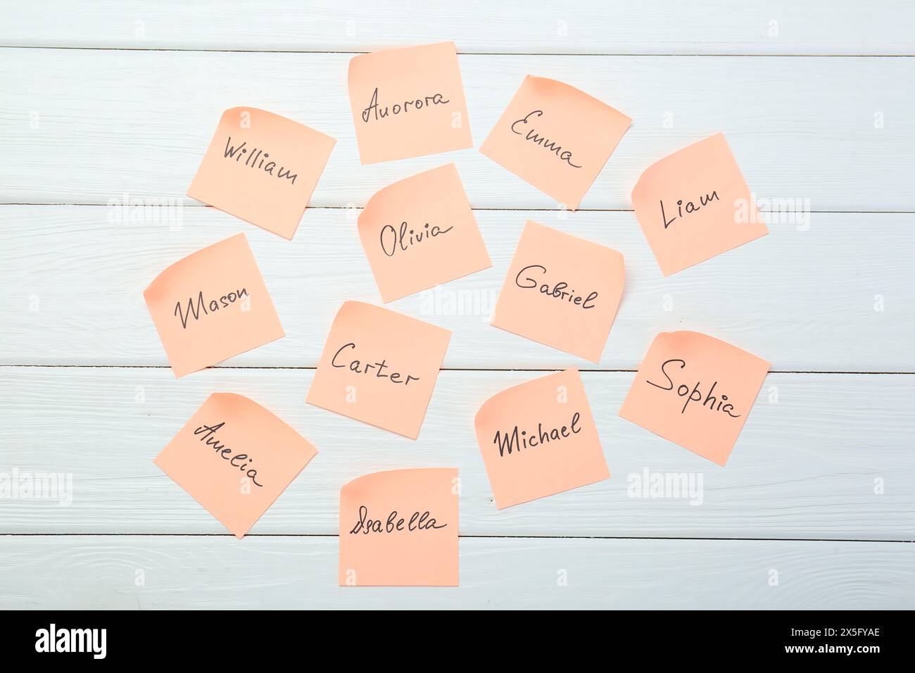 Paper stickers with different names on white wooden background, flat ...
