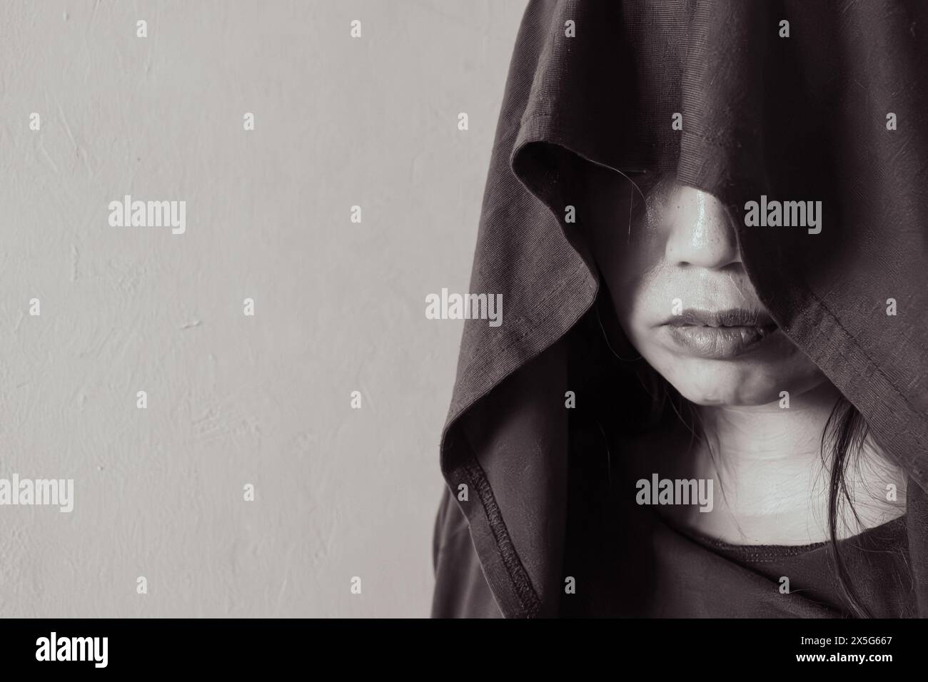 portrait of a woman donned in a hood and steampunk goggles, her gaze intensified by the striking contrast of sunlight and shadows Stock Photo