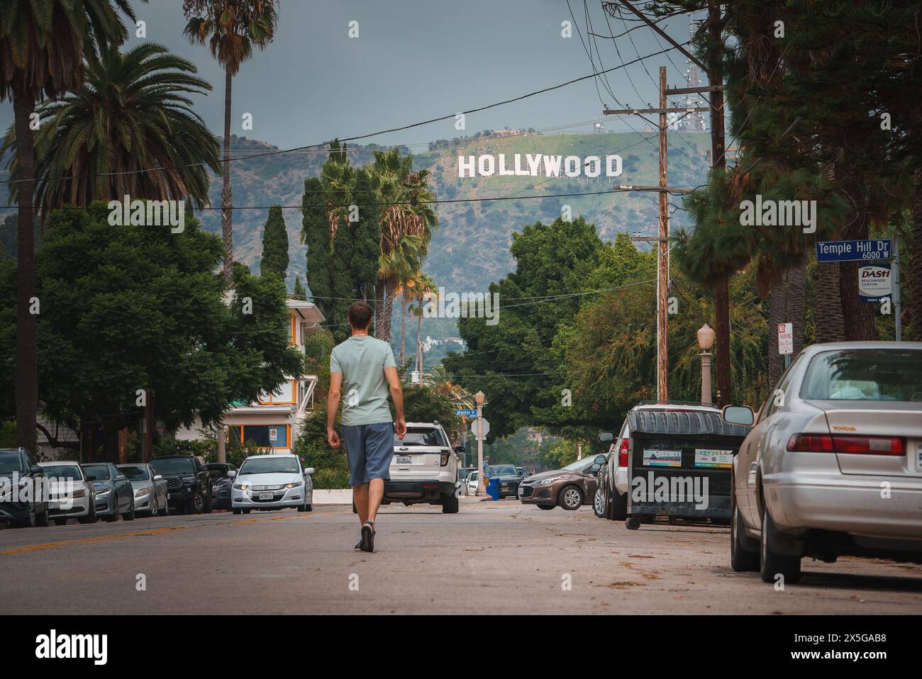 Person walking towards Hollywood sign on residential street in Los Angeles Stock Photo