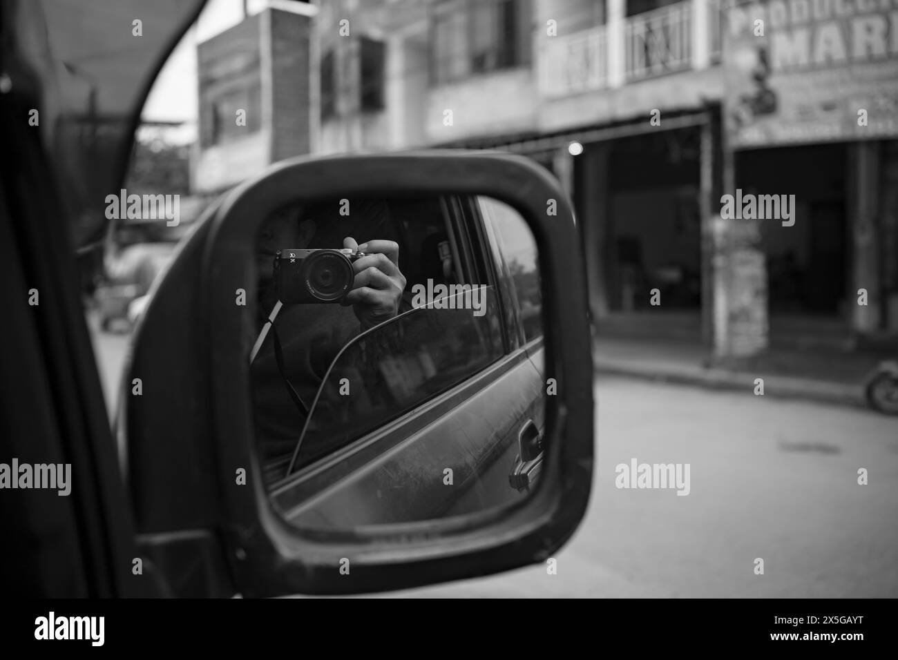 Man taking picture reflected in the rearview mirror. Stock Photo