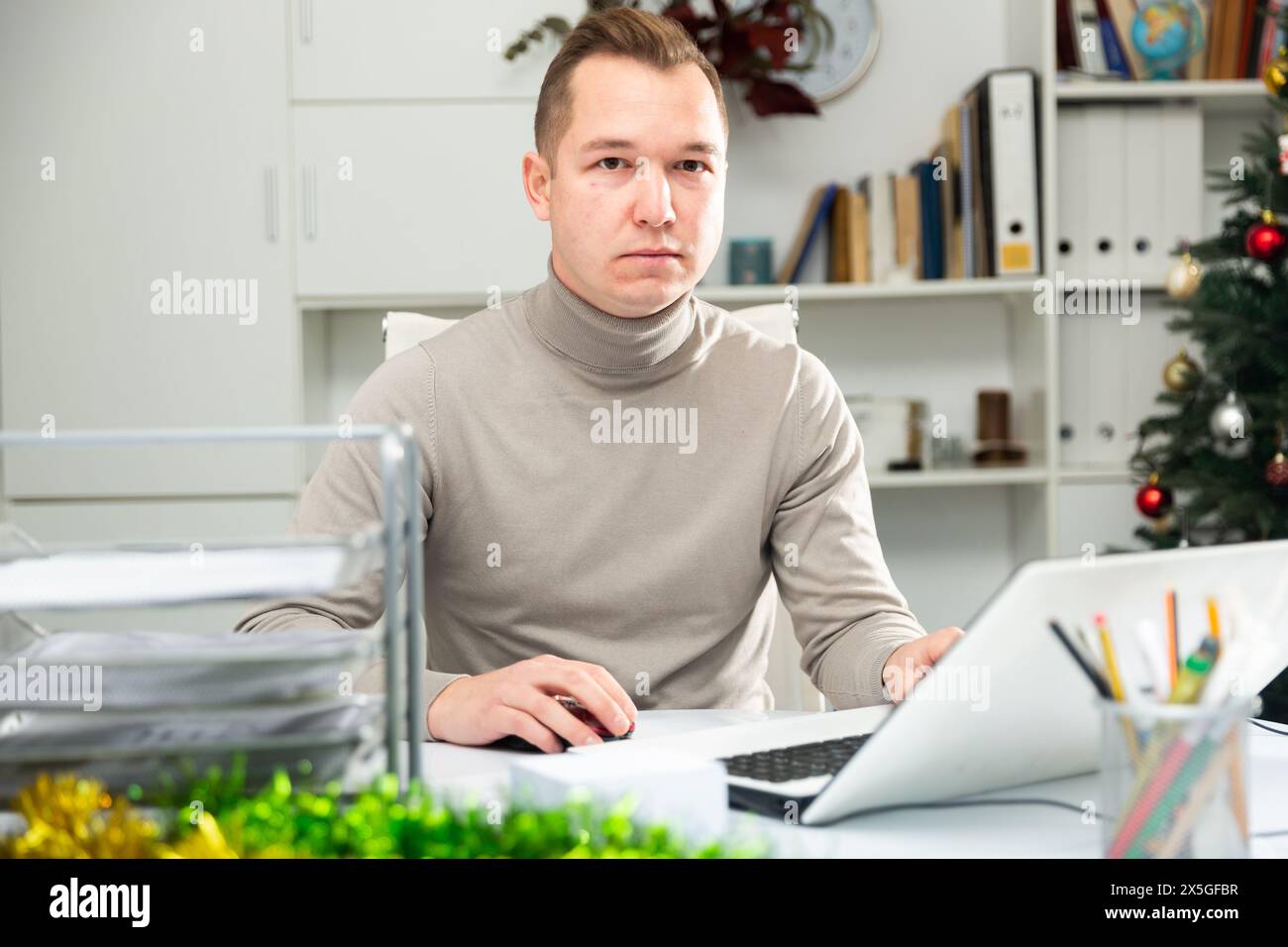 Man office worker using laptop during Christmastime Stock Photo