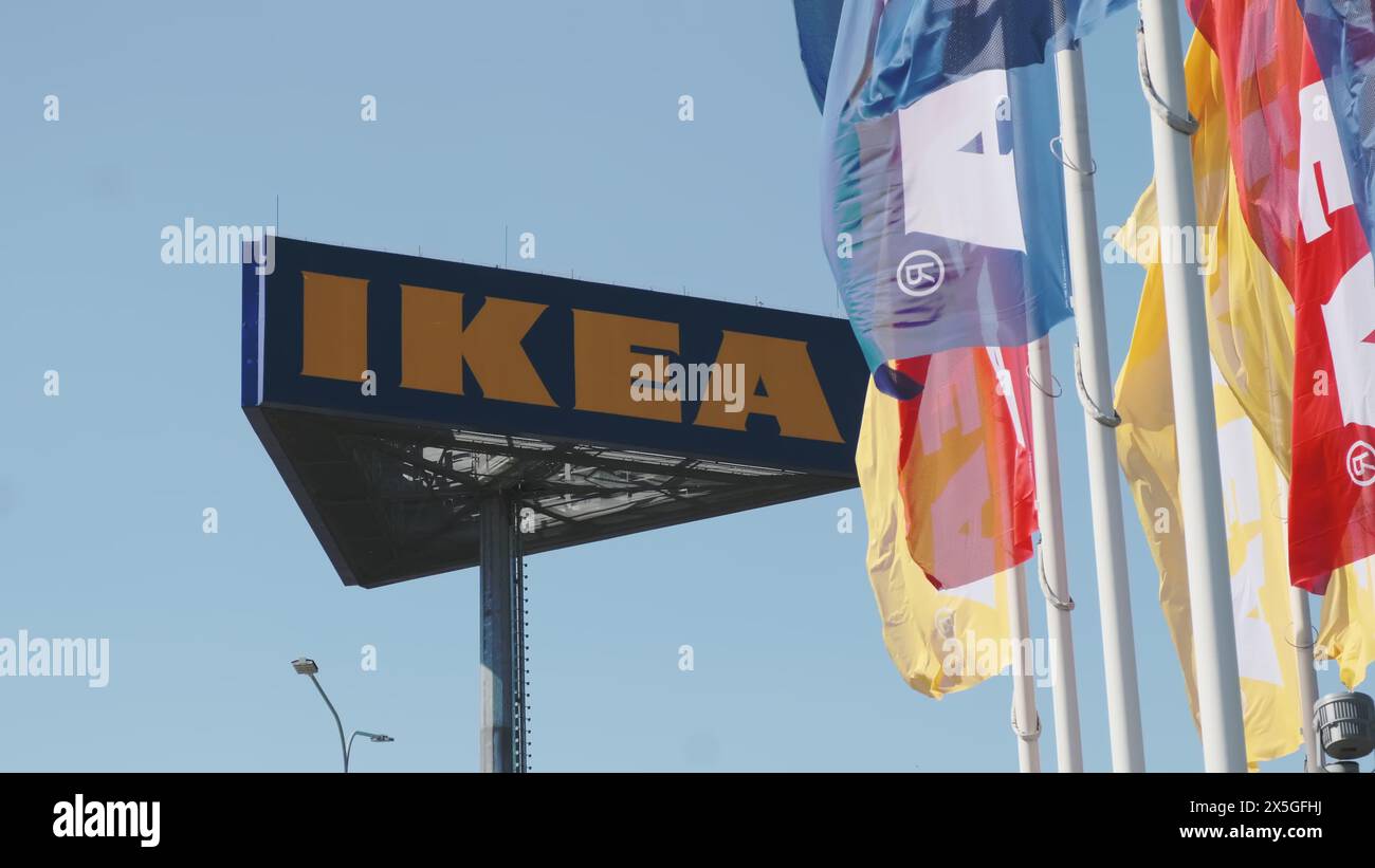 PRAGUE, CZECHIA -APRIL, 2024: IKEA flags waving in the wind against sky and signboard. Stock Photo