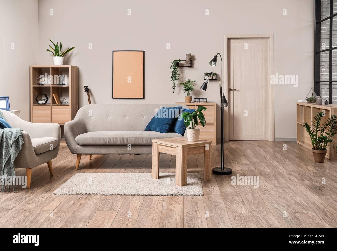 Interior of light living room with grey sofa, table and plants Stock ...