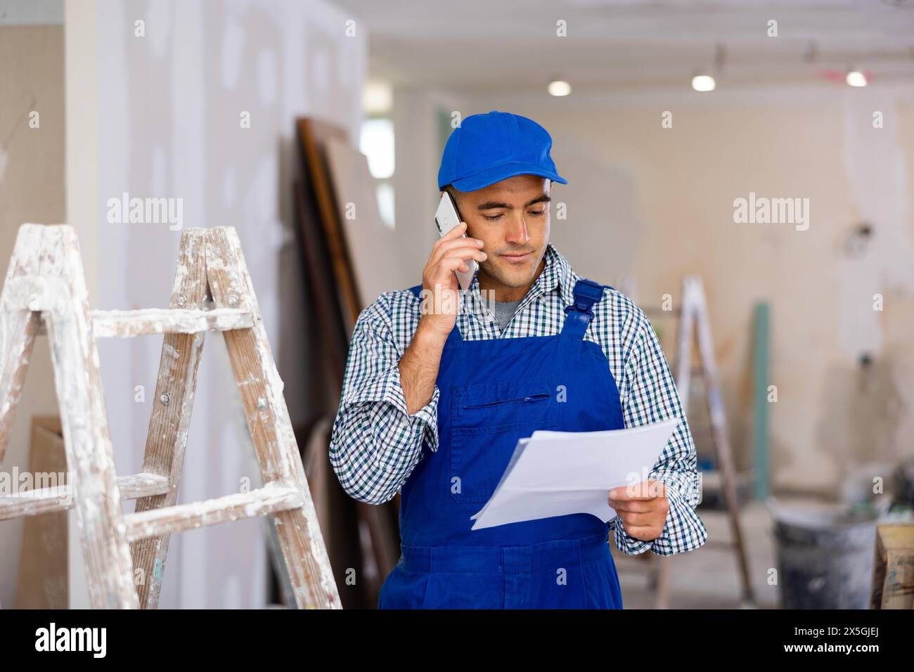 Young foreman with documents in his hands is talking on a mobile phone Stock Photo