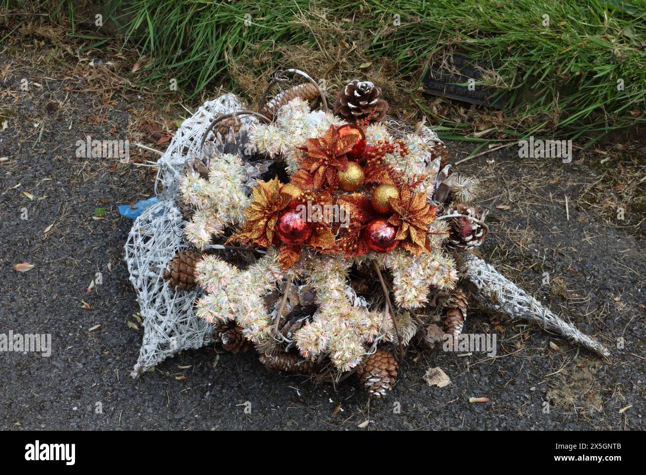 A colourful christmas wreath laying on the ground in a cemetery Stock Photo