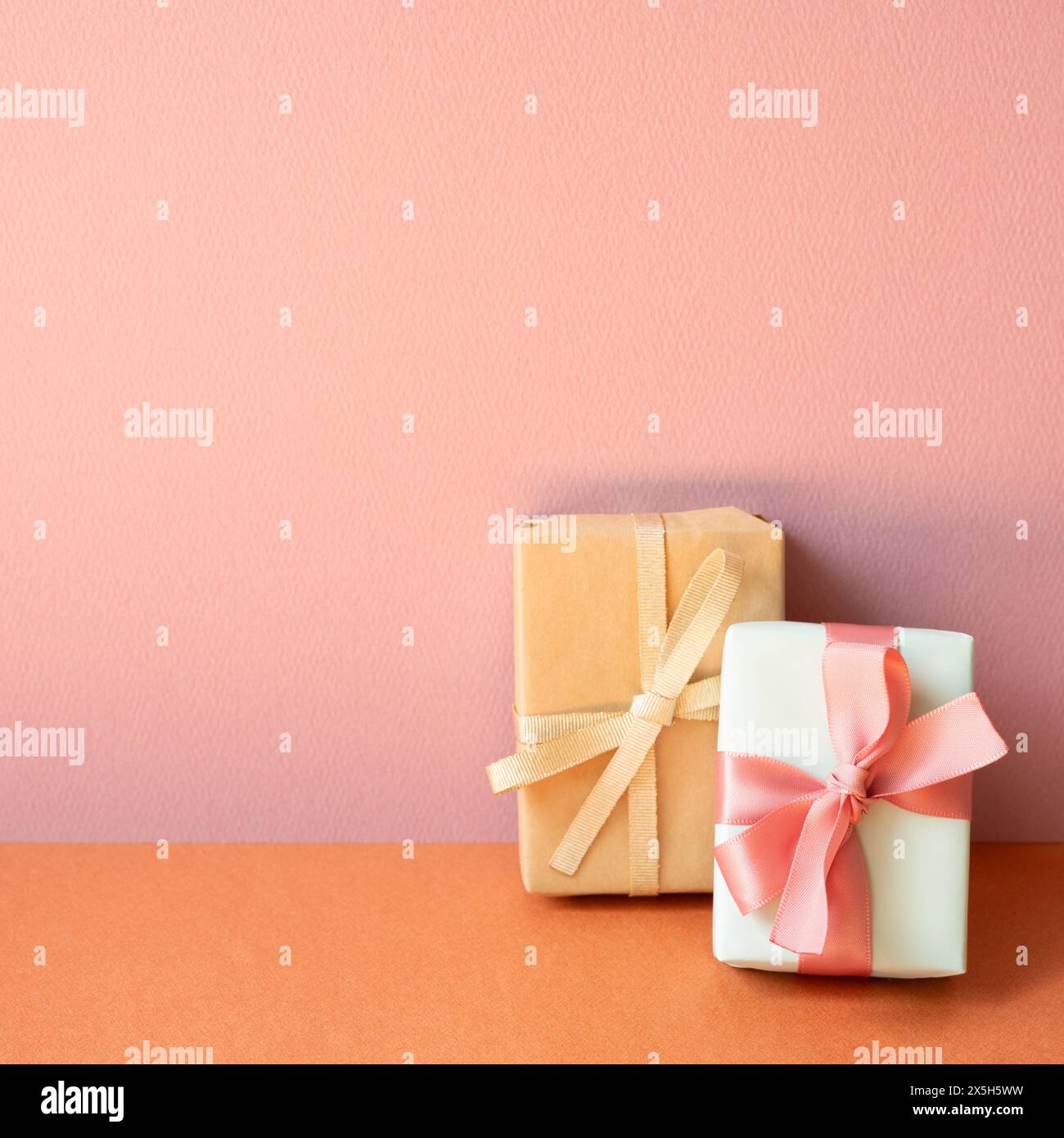 Gift boxes on orange table. pink wall background with copy space Stock Photo