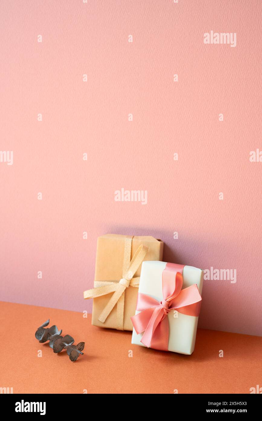 Gift boxes and eucalyptus leaf on orange table. pink wall background with copy space Stock Photo