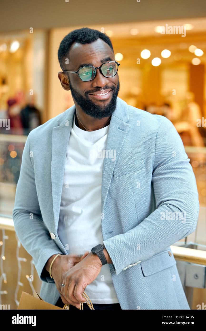 handsome bearded man in stylish suit, jacket, watch standing at shopping mall. time for sales, black friday, buying, purchase Stock Photo