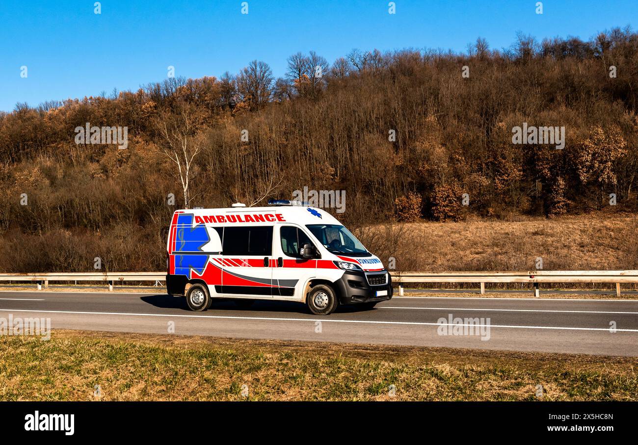 Ambulance van on highway at sunset. Ambulance car responding to the scene of an emergency. Stock Photo