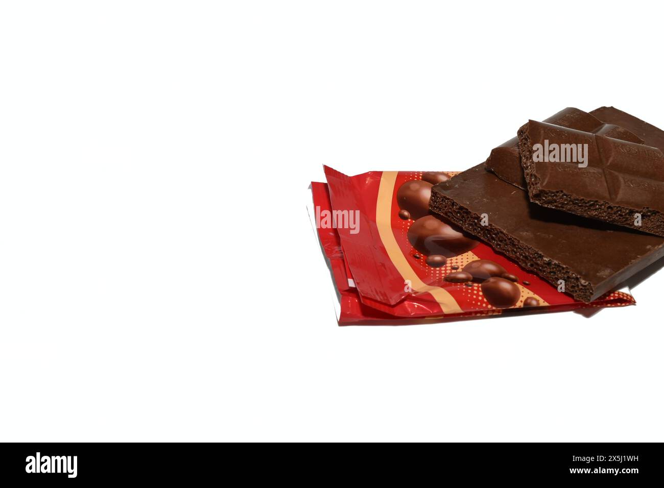 There is a chocolate bar on a package on a white background. Stock Photo