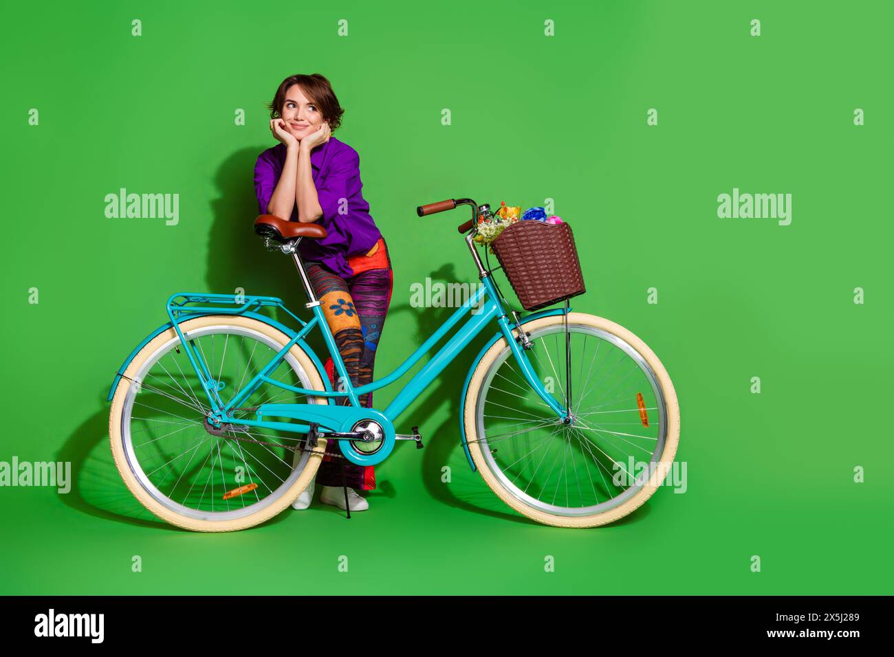 Photo portrait of funny young dreamy woman touch cheeks enjoy summer season driving bicycle isolated on green color background Stock Photo