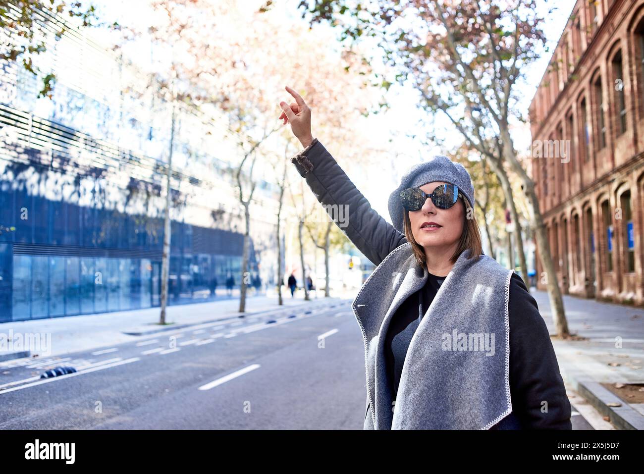 Stylish woman hailing a cab on a quiet city street Stock Photo