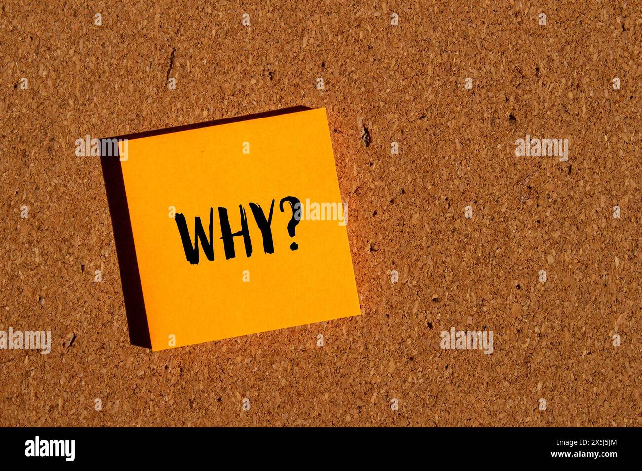 Why ? question written on orange paper sticker with brown background ...