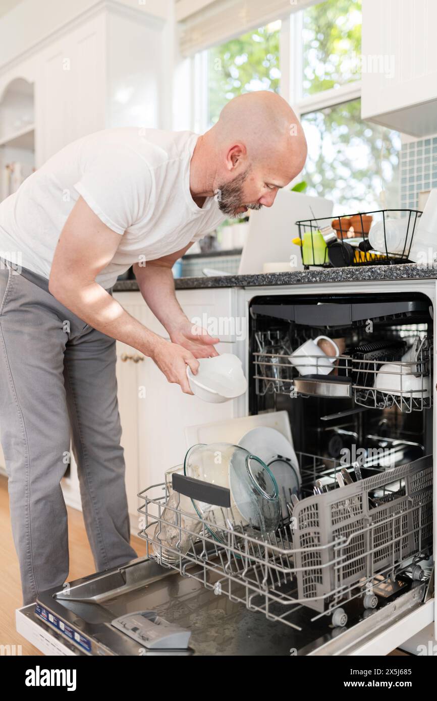 Close up of man loading dishwasher Stock Photo
