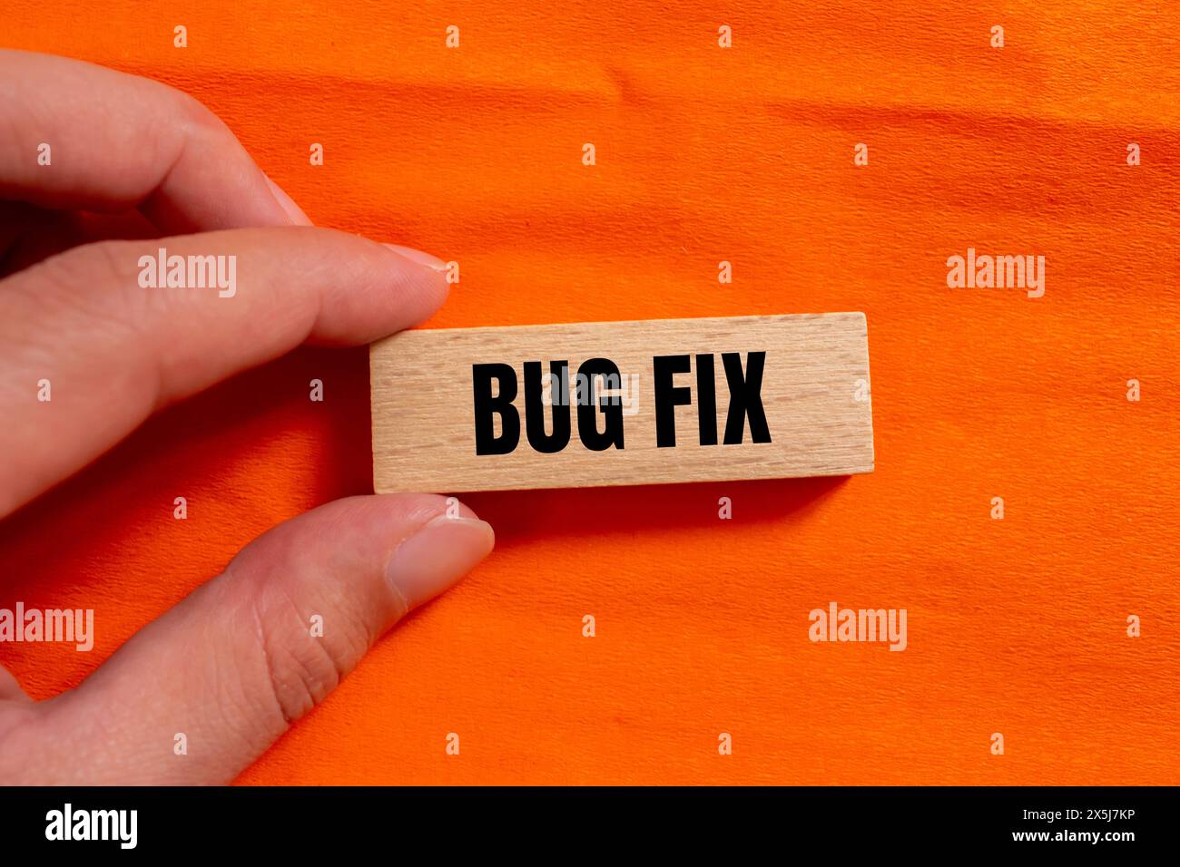 Bug fix words written on wooden block with orange background ...