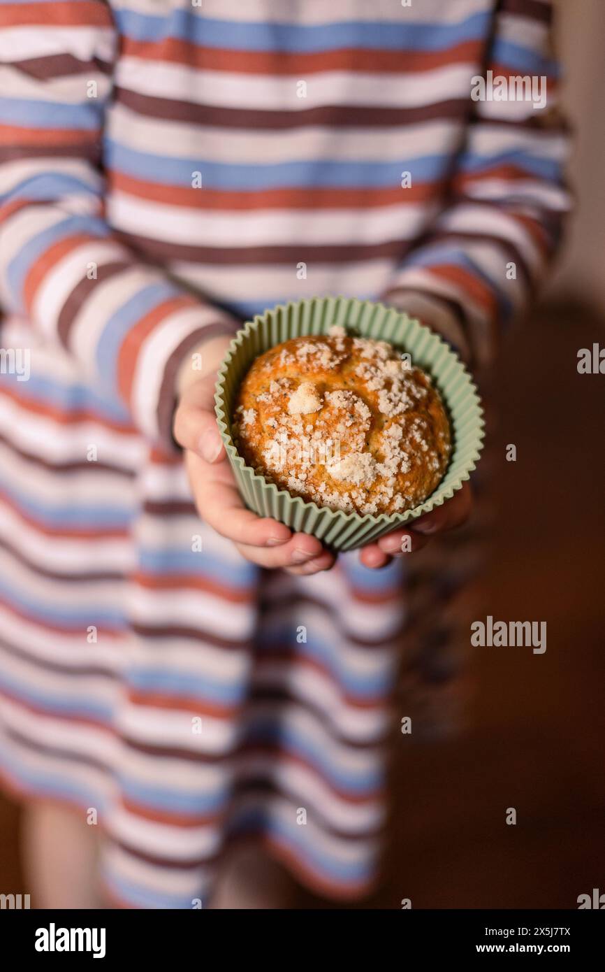Small hands grasp a muffin in a silicone cup Stock Photo
