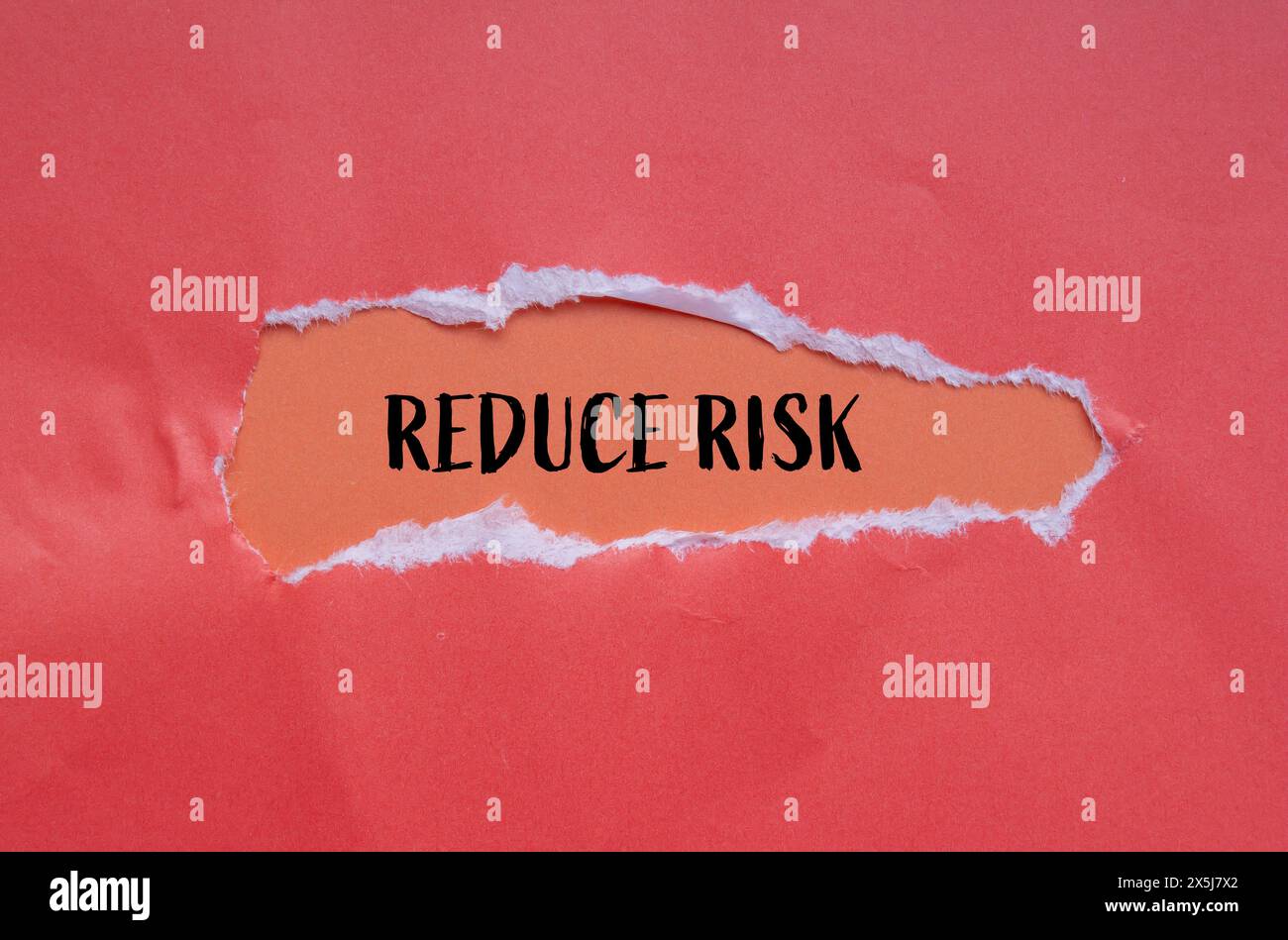 Reduce risk words written on torn paper with orange background. Conceptual reduce risk symbol. Copy space. Stock Photo