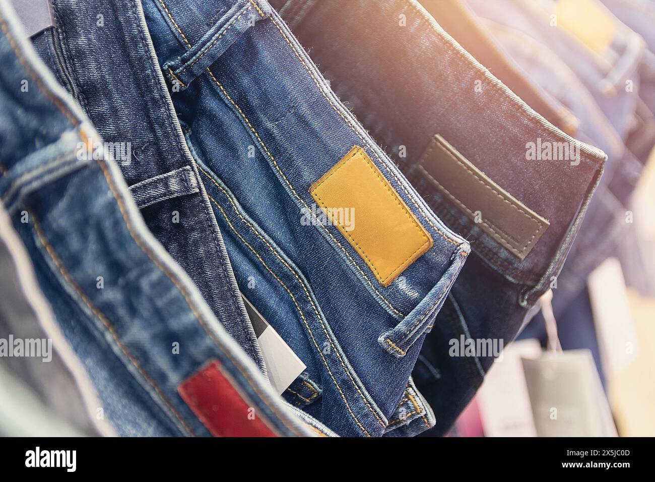 Many jeans hanging on arack. Row of pants denim jeans hanging in closet, concept of buy , sell , shopping and jeans fashion Stock Photo
