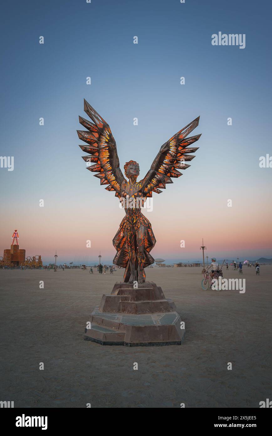 Angel sculpture with expansive wings in desert festival sunset Stock Photo