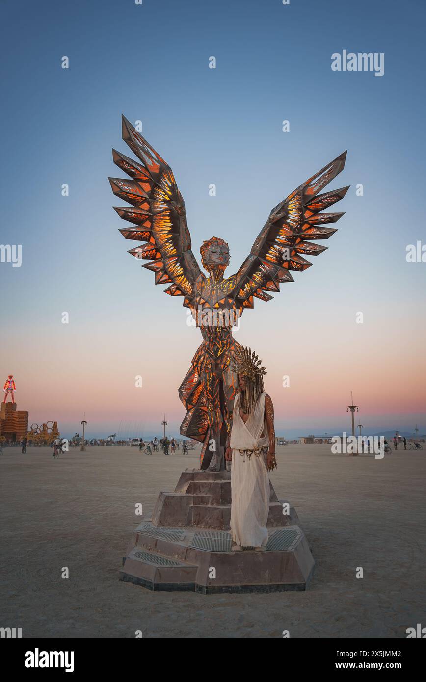Desert festival art Angel sculpture at dusk with figure in ceremonial attire Stock Photo