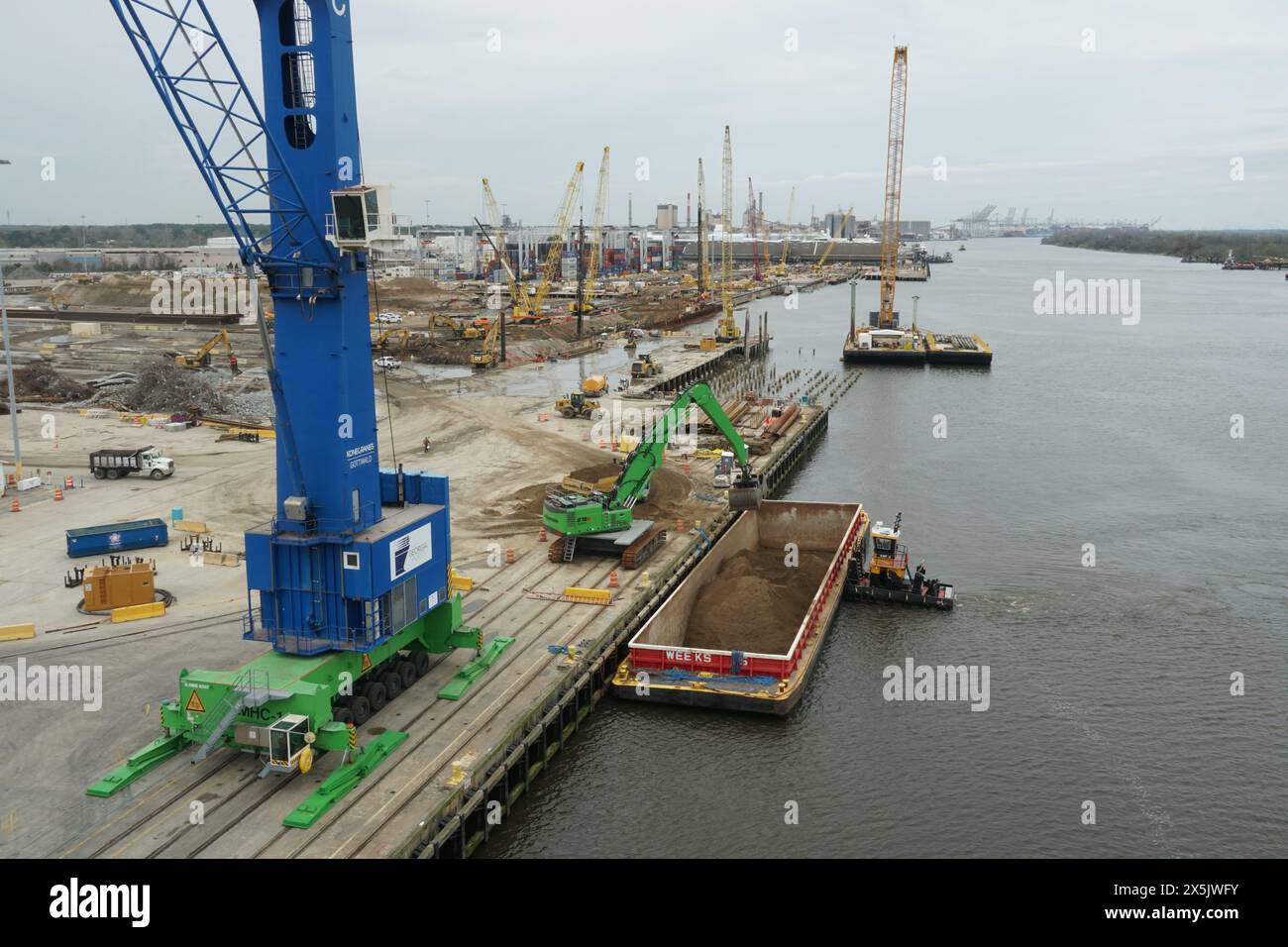 Tugboat with barge, blue mobile crane and other heavy industrial ...