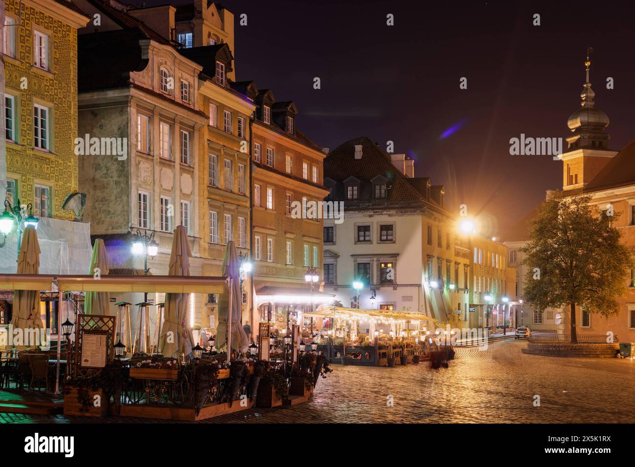 Castle Square Plac Zamkowy at night with outdoor seating restaurants around traditional low-rise buildings, Old Town, Warsaw, Poland, Europe Copyright Stock Photo