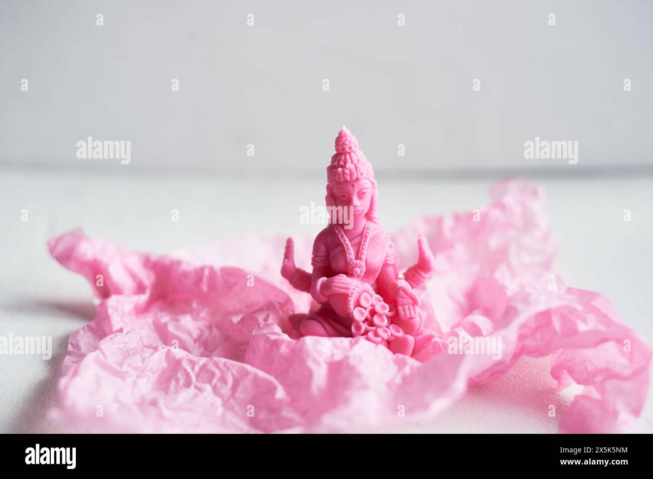 A pink candle is placed on a pink petal, resembling a delicate flower. The magenta hue contrasts beautifully with the natural material, creating a stu Stock Photo