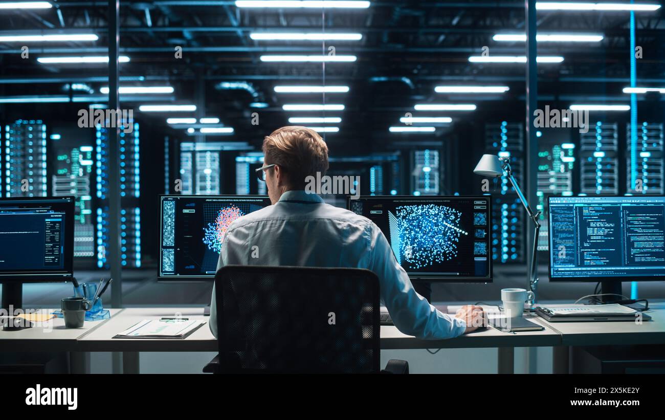 Professional IT Programer Working in Data Center on Desktop Computer with Two Displays, while Doing Development of Software and Hardware. Displays Show Blockchain, Data Network Architecture Stock Photo